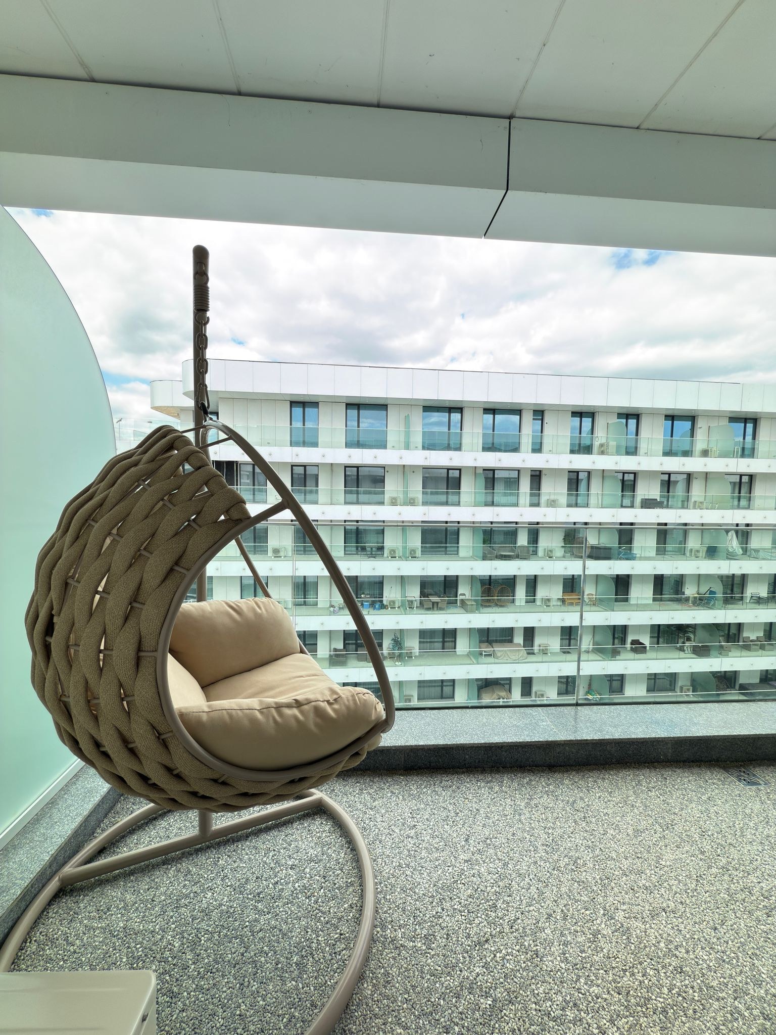 Fotoliu suspendat pe balcon, cu vedere spre clădirile complexului